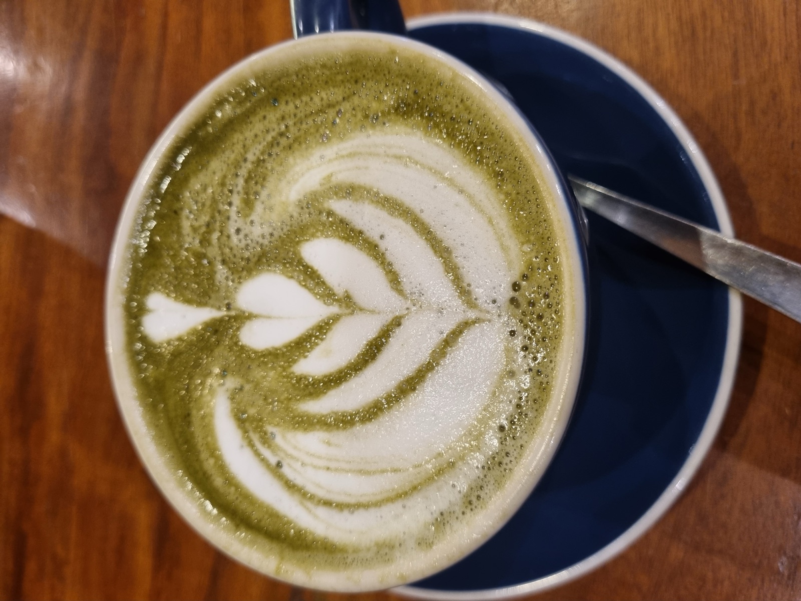A bright green matcha latte in a glass cup with steamed milk — the standard café-style matcha drink served across Milwaukee