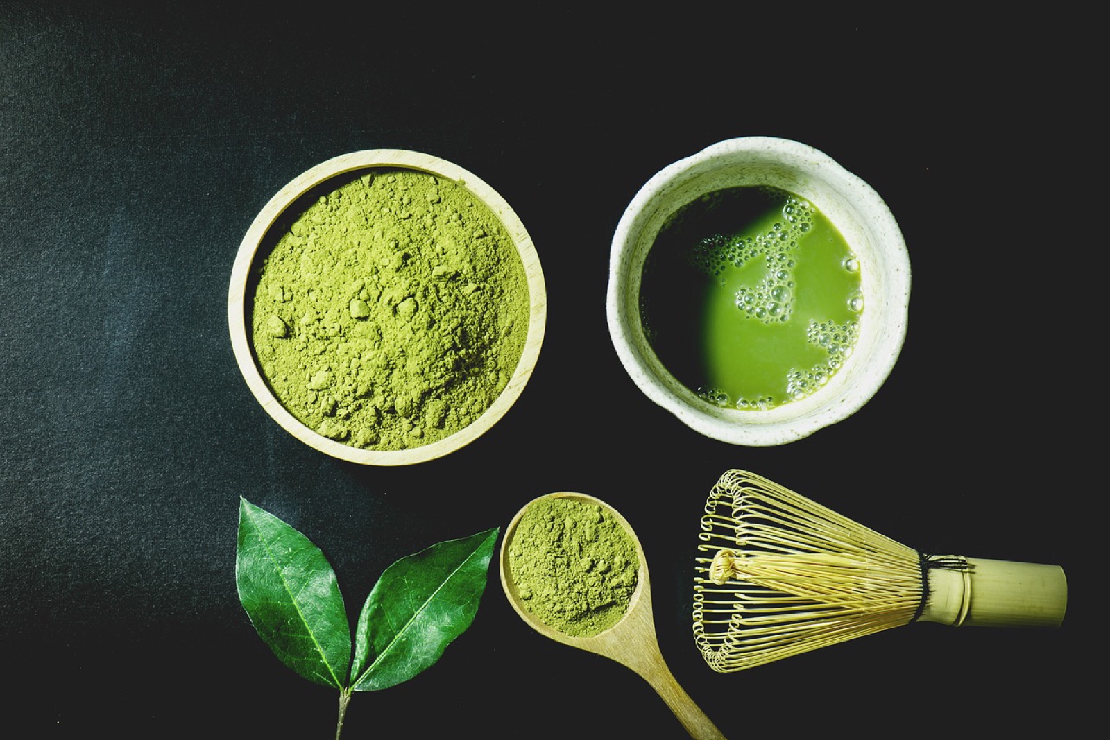 Bright green matcha being whisked with a chasen bamboo whisk in a chawan tea bowl — the traditional Japanese preparation served at Jasher's Organic Tea House in Bay View